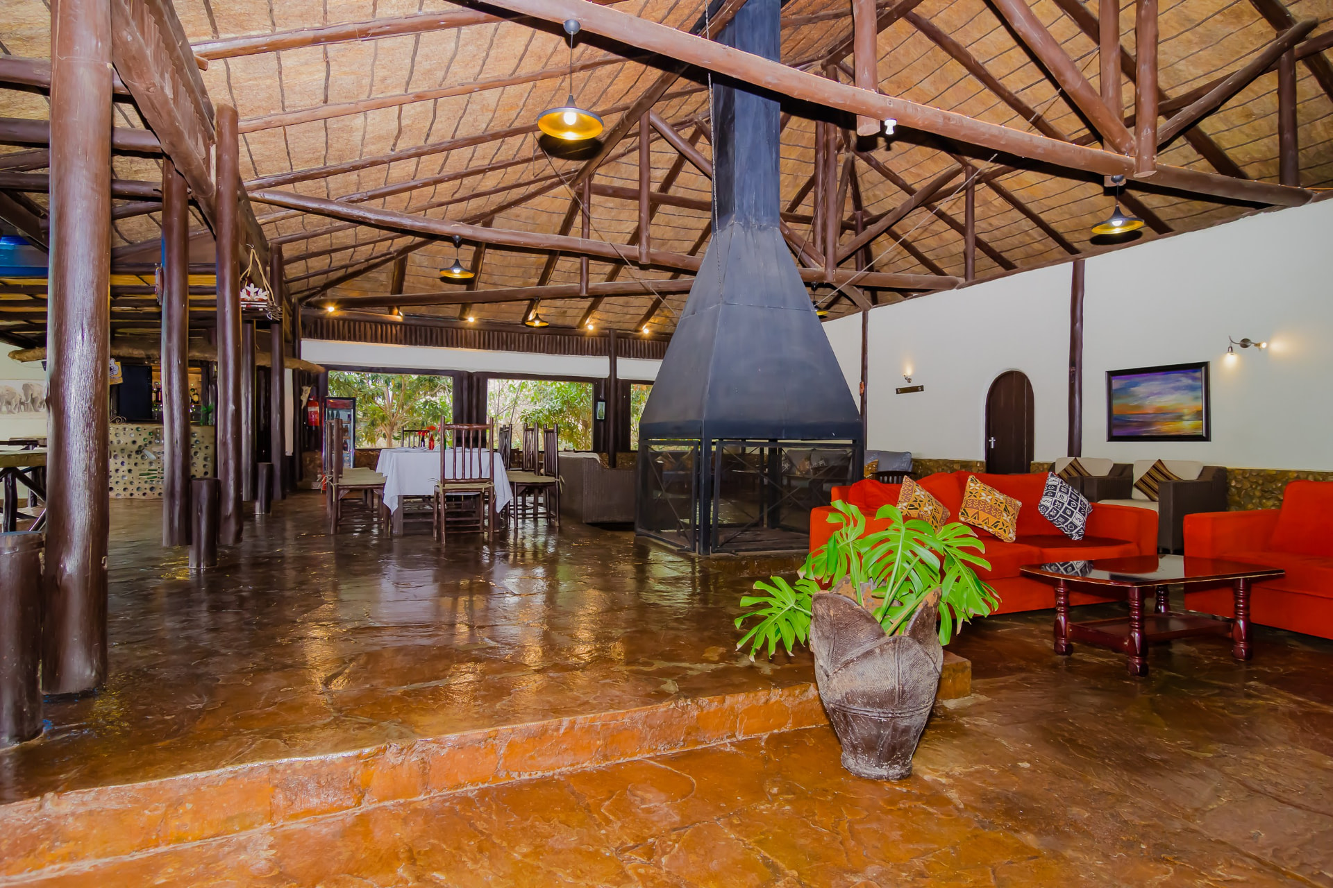 Thatched dining lounge with fireplace and red sofas