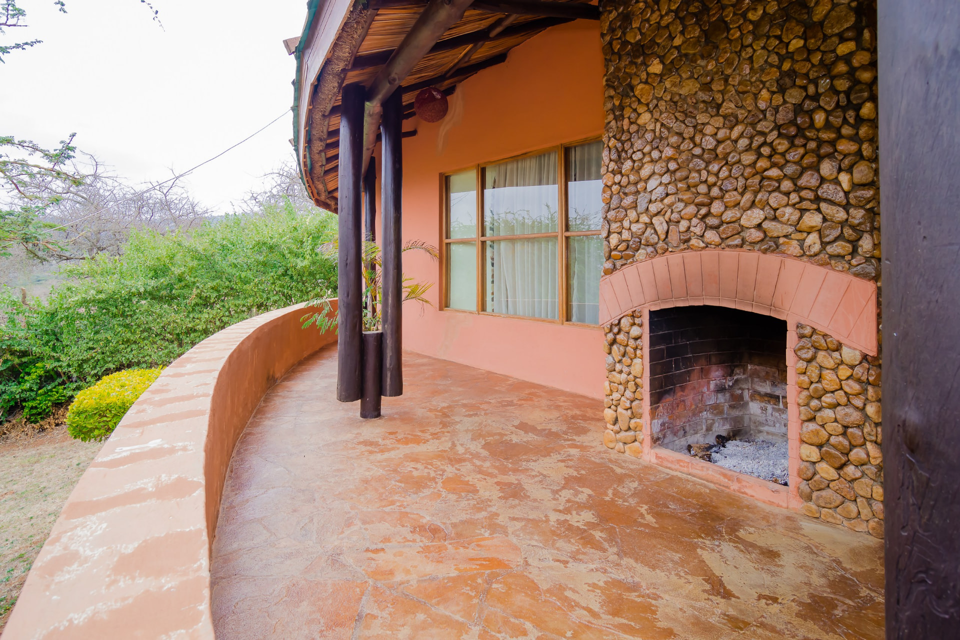 Veranda with a stone fireplace surrounded by greenery