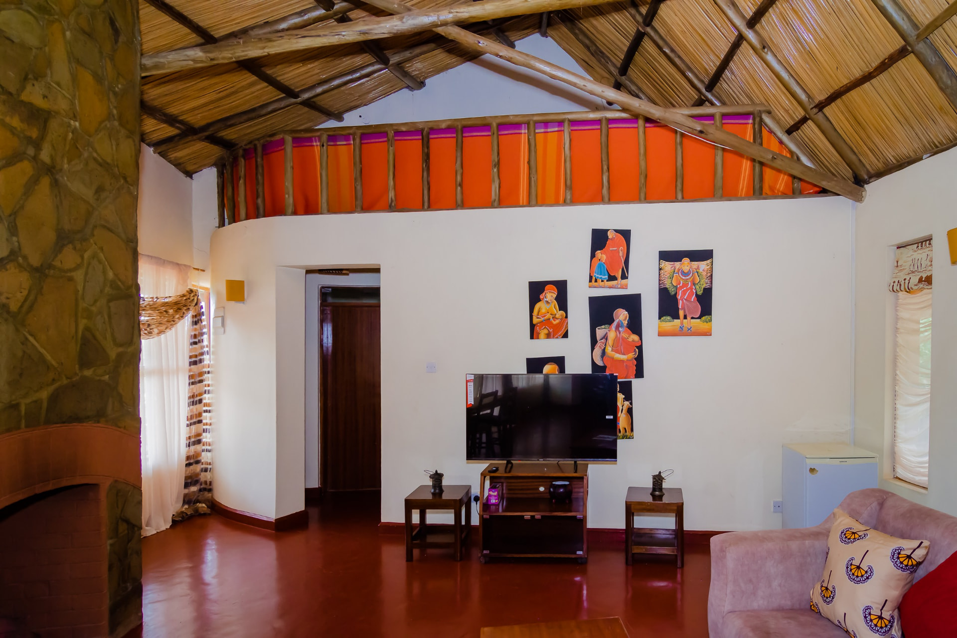 Lounge area with TV, artwork and thatched ceiling