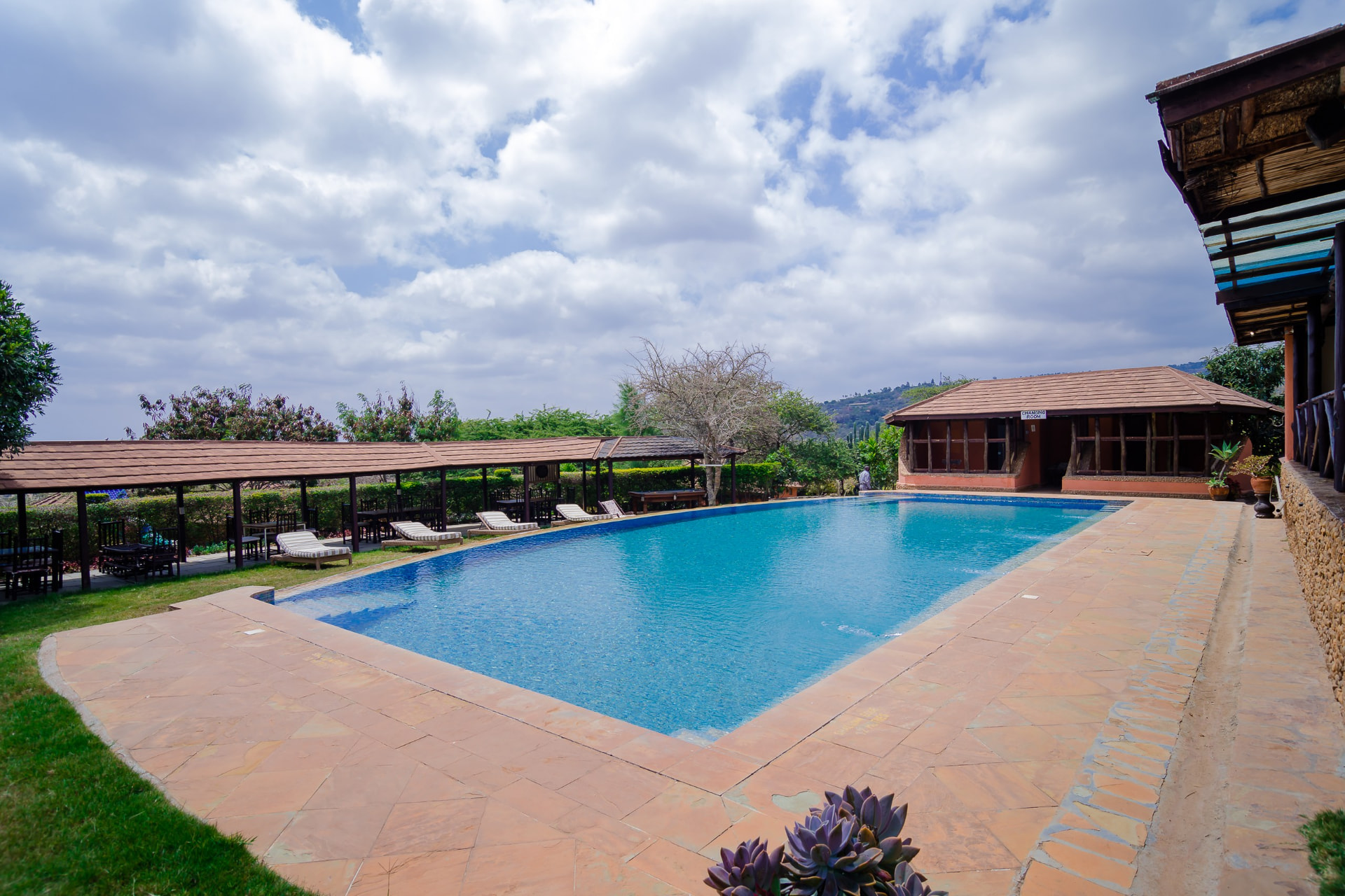 Resort pool with shaded loungers and hill views