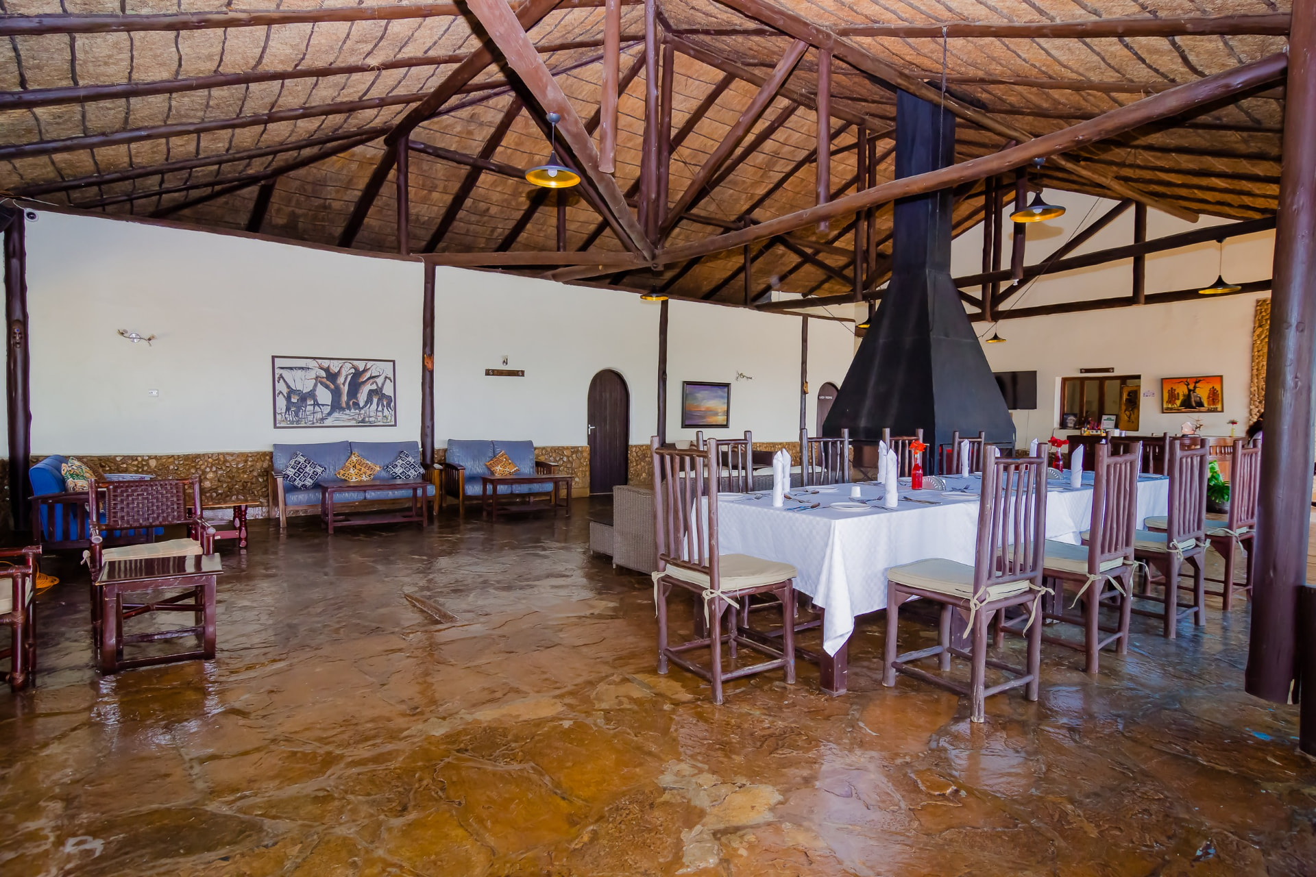 Thatched dining hall with long table, fireplace and polished floor