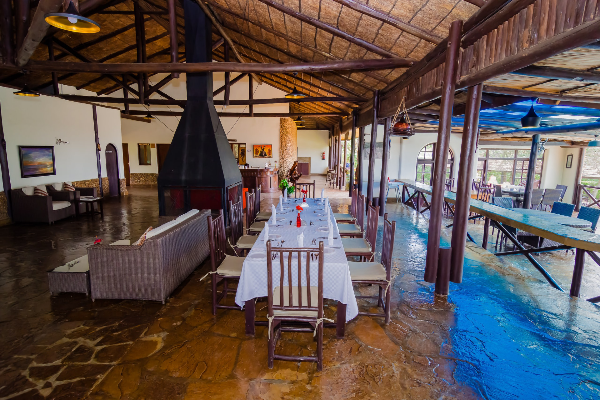 Open dining and lounge area under a thatched roof with central fireplace